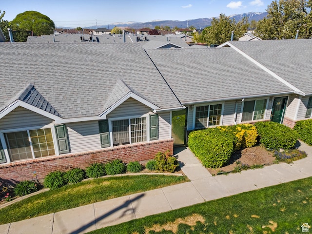single story home featuring roof with shingles, a mountain view, and brick siding