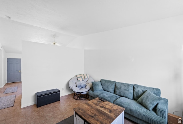 living area featuring baseboards, tile patterned flooring, and vaulted ceiling