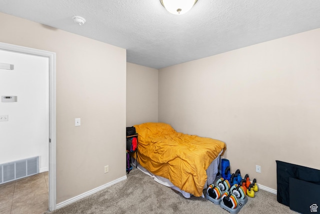 bedroom featuring a textured ceiling, carpet floors, visible vents, and baseboards