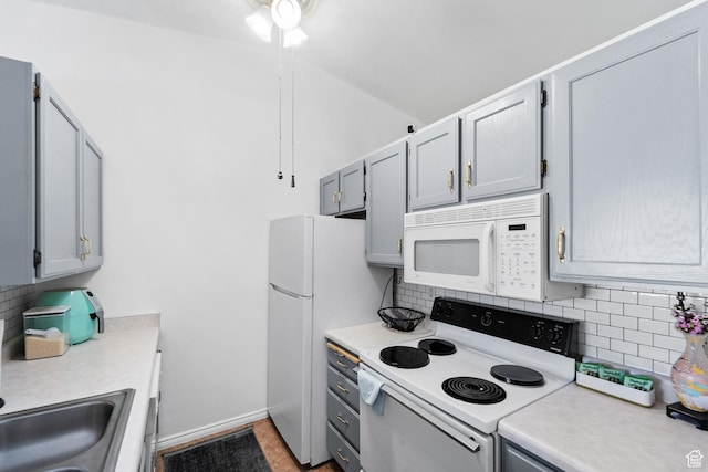 kitchen with backsplash, light countertops, baseboards, and white appliances