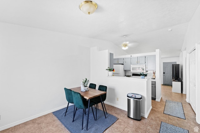 dining space featuring light tile patterned floors, ceiling fan, baseboards, and lofted ceiling