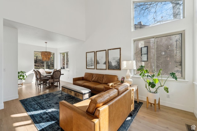 living area with light wood-style floors, a high ceiling, and baseboards