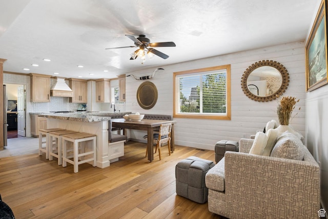 living room featuring wooden walls, a ceiling fan, recessed lighting, and light wood-style flooring