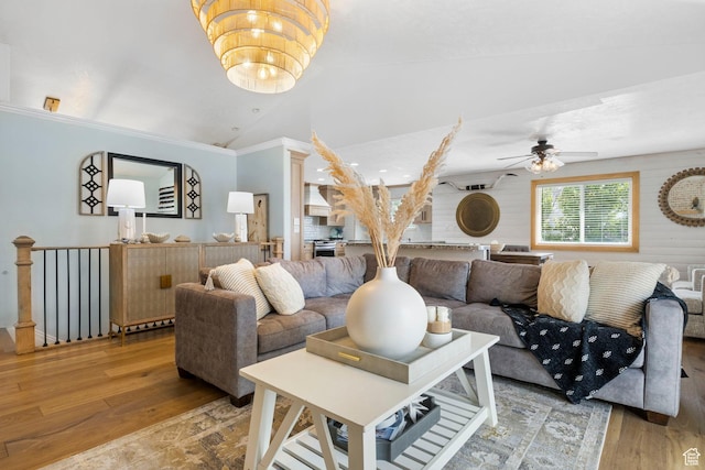 living area with light wood-style floors, ornamental molding, a ceiling fan, and lofted ceiling