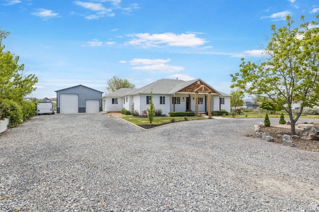 view of front facade with a detached garage, an outbuilding, and gravel driveway