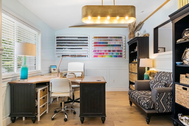 home office with a wainscoted wall, light wood-type flooring, and lofted ceiling