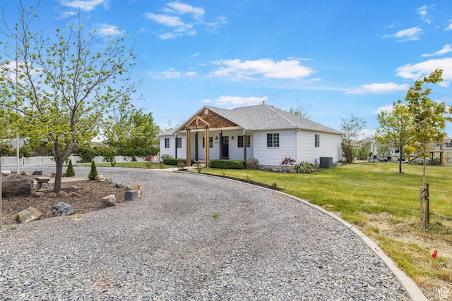 view of front of property with roof with shingles, central AC, a front yard, curved driveway, and covered porch