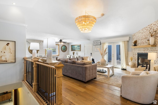 living area with a fireplace, ceiling fan with notable chandelier, and light wood finished floors