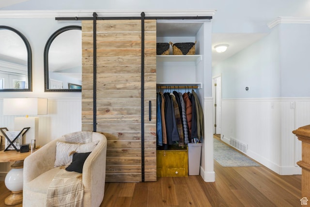 living area with a wainscoted wall, wood finished floors, and visible vents