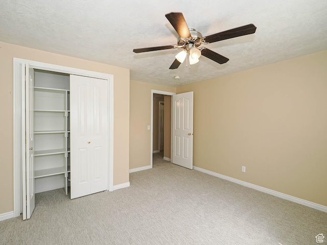 unfurnished bedroom with light carpet, a textured ceiling, baseboards, a ceiling fan, and a closet
