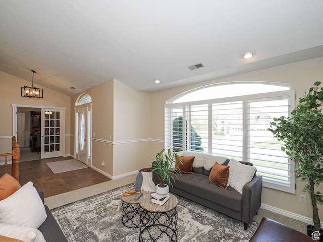 living room featuring baseboards, vaulted ceiling, visible vents, and a chandelier