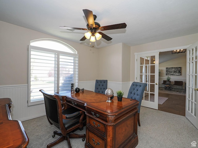 carpeted office with wainscoting, french doors, and ceiling fan with notable chandelier