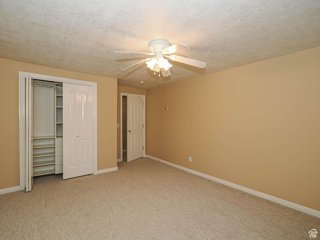 unfurnished bedroom with a textured ceiling, a closet, baseboards, and light colored carpet