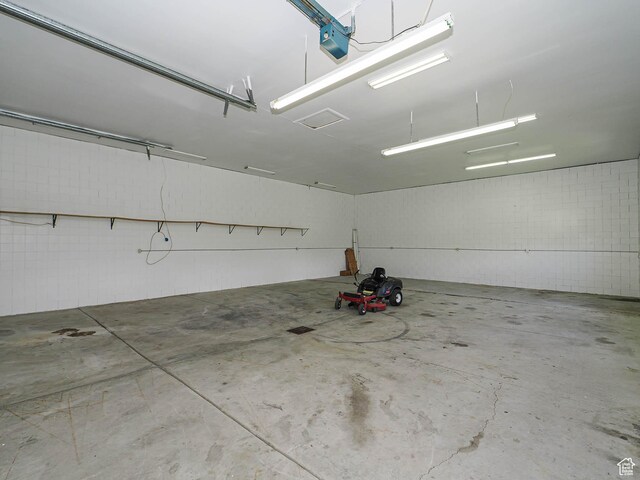 garage featuring concrete block wall and a garage door opener