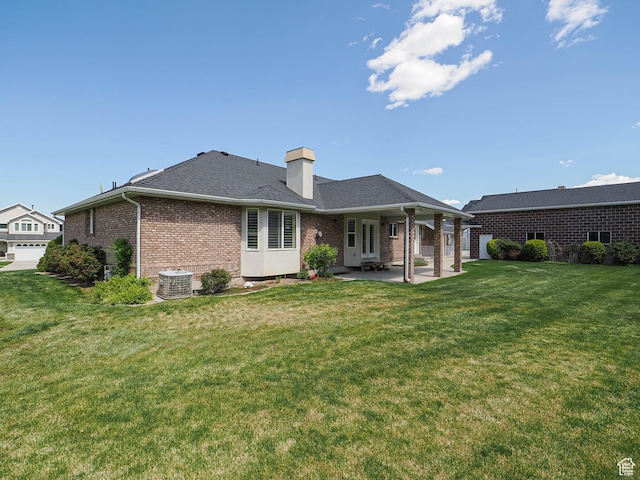 back of house featuring roof with shingles, cooling unit, brick siding, a lawn, and a patio