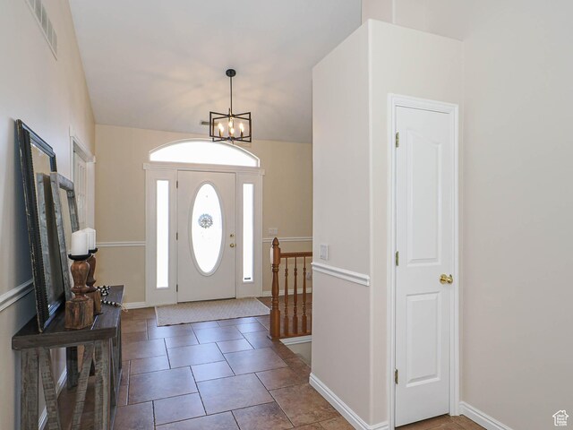 tiled entrance foyer featuring baseboards, visible vents, and a notable chandelier