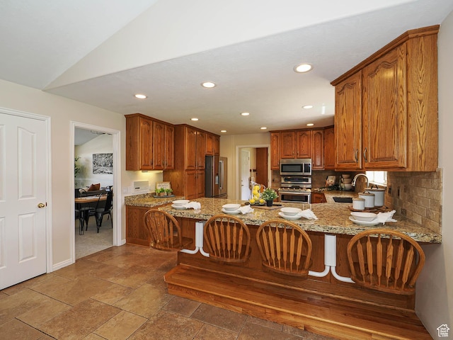 kitchen with a sink, backsplash, a peninsula, appliances with stainless steel finishes, and recessed lighting