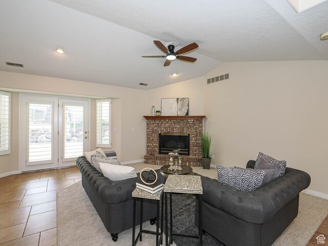 living room with vaulted ceiling, visible vents, a fireplace, and ceiling fan