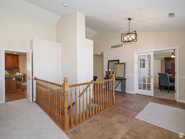 corridor featuring visible vents, french doors, an upstairs landing, a chandelier, and high vaulted ceiling