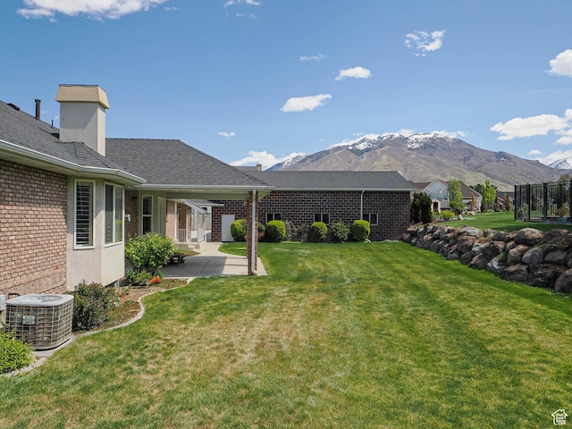 view of yard featuring central air condition unit, a patio area, and a mountain view