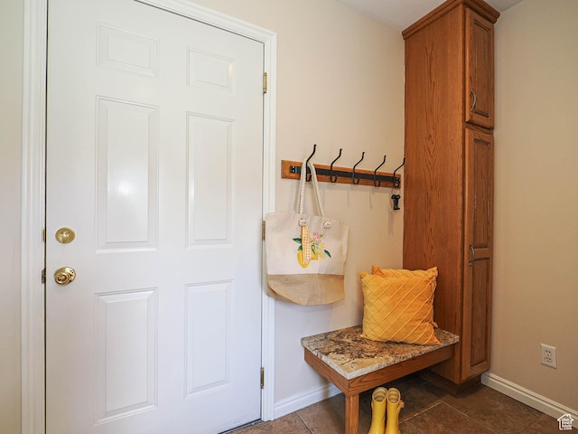mudroom featuring dark tile patterned floors and baseboards