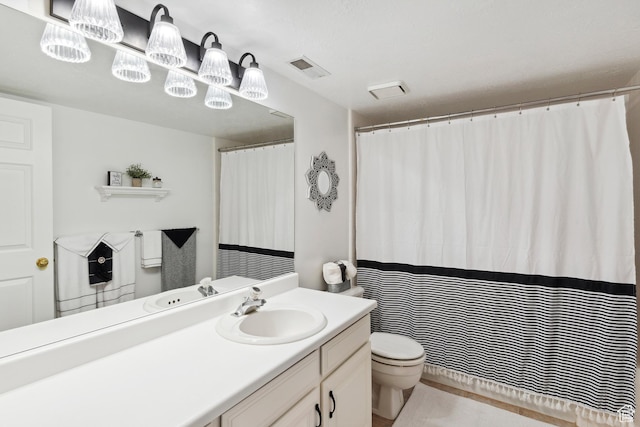 bathroom featuring toilet, vanity, and visible vents