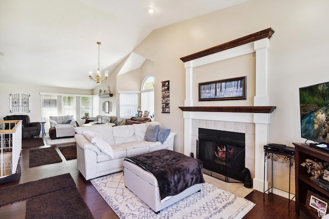 living room featuring a tiled fireplace, a chandelier, high vaulted ceiling, and wood finished floors