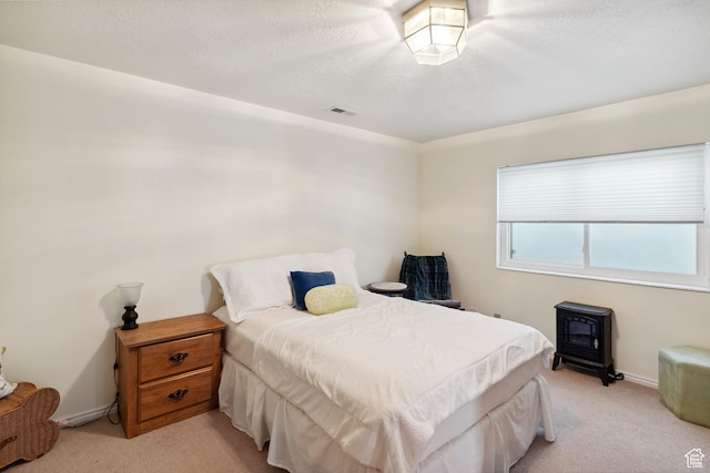 bedroom featuring light colored carpet, a wood stove, baseboards, and visible vents