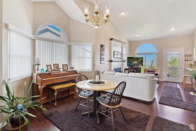 dining area featuring recessed lighting, an inviting chandelier, high vaulted ceiling, wood finished floors, and a fireplace