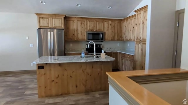 kitchen with stainless steel appliances, lofted ceiling, an island with sink, a sink, and recessed lighting
