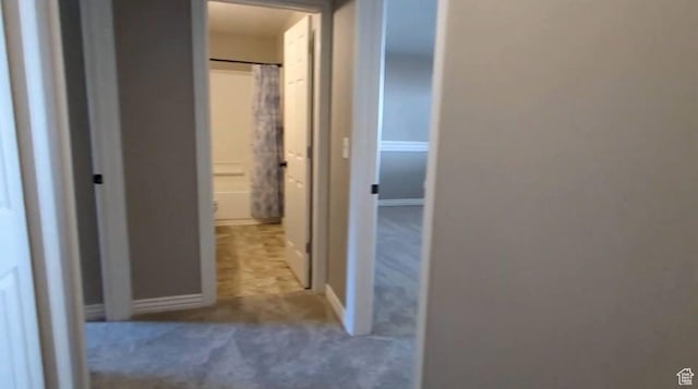 hallway with carpet flooring and baseboards