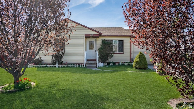 view of front of house featuring entry steps, an attached garage, a shingled roof, and a front lawn
