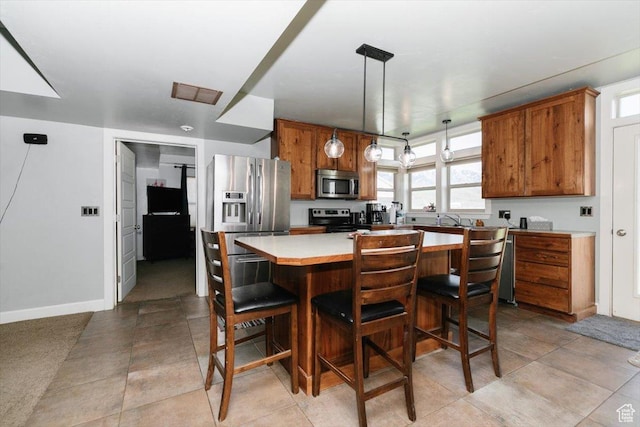 9 W Cedar Ln, Franklin, ID 83237 - kitchen featuring stainless steel appliances, brown cabinets, light countertops, a center island, and a breakfast bar