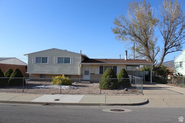 tri-level home featuring a carport, driveway, and a fenced front yard