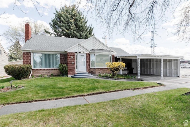 view of front facade with concrete driveway, a front lawn, a chimney, an attached carport, and brick siding