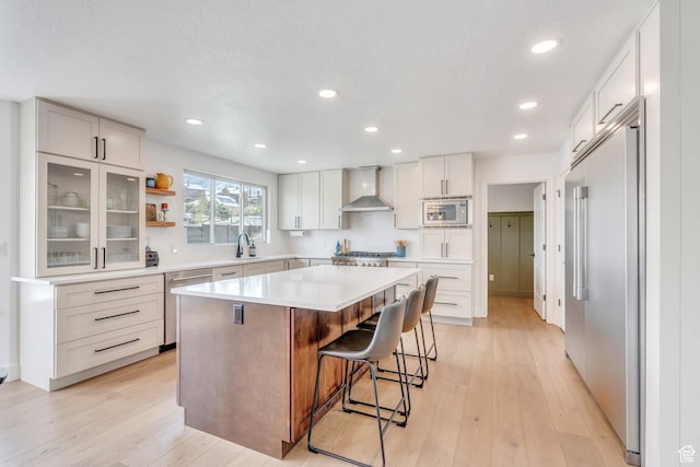 2696 W Red Robin Ct, Lehi, UT 84043 - kitchen featuring a breakfast bar, light wood-style flooring, wall chimney range hood, and built in appliances
