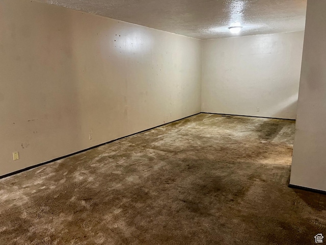 carpeted spare room featuring baseboards and a textured ceiling