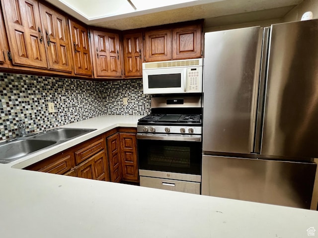 kitchen featuring decorative backsplash, appliances with stainless steel finishes, a sink, and light countertops