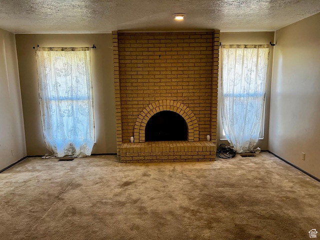 unfurnished living room with baseboards, carpet floors, a textured ceiling, and a fireplace