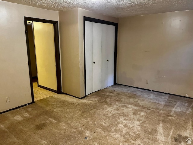 unfurnished bedroom featuring carpet floors, a textured ceiling, and a closet