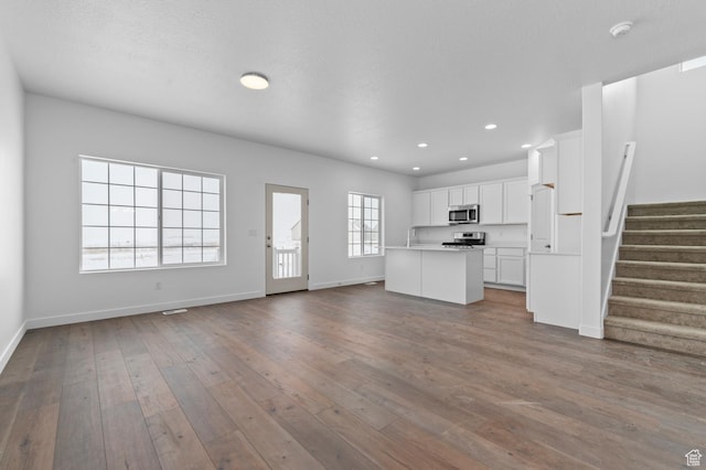 6717 N Tulle Mtn, Eagle Mountain, UT 84005 - unfurnished living room featuring a sink, dark wood finished floors, baseboards, recessed lighting, and stairway