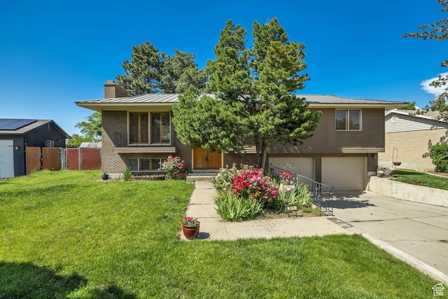 371 E 6770 S, Midvale, UT 84047 - split level home featuring a garage, concrete driveway, a chimney, metal roof, and a standing seam roof