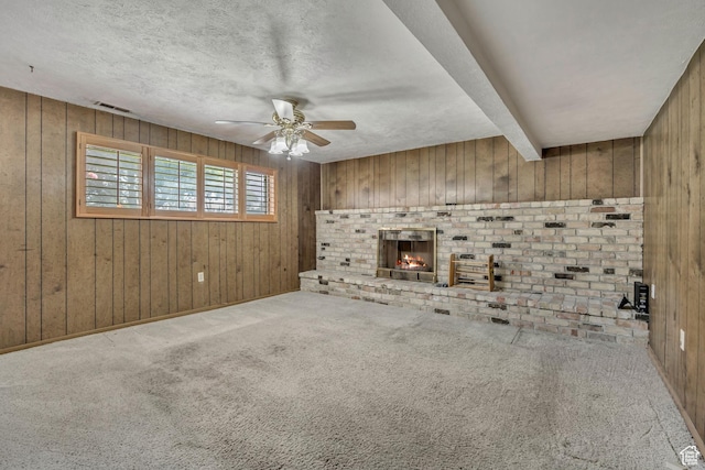 371 E 6770 S, Midvale, UT 84047 - unfurnished living room with wood walls, a ceiling fan, a brick fireplace, a textured ceiling, and carpet