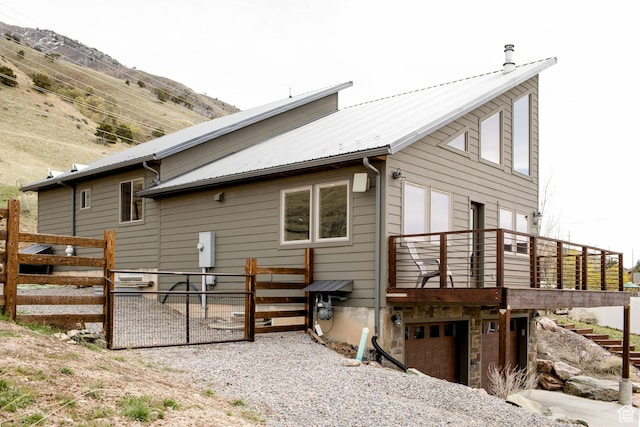 rear view of property featuring metal roof, an attached garage, and fence