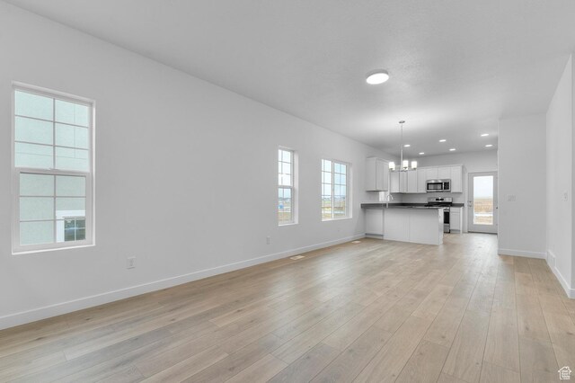 6737 N Tulle Mtn, Eagle Mountain, UT 84005 - unfurnished living room featuring baseboards, light wood-style flooring, a chandelier, and recessed lighting