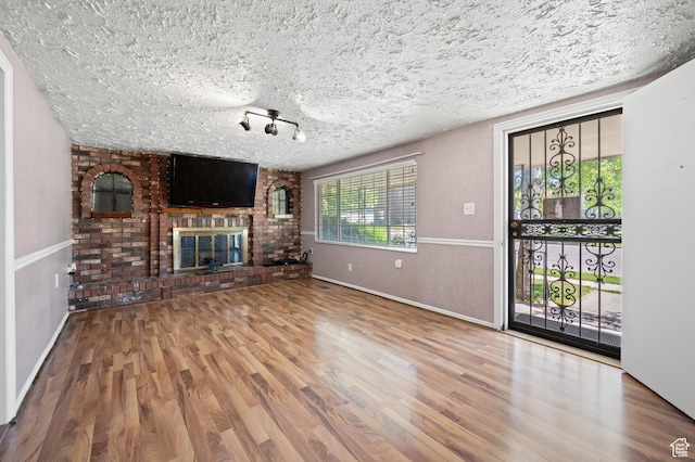 336 W 200 N, Bountiful, UT 84010 - unfurnished living room with baseboards, a brick fireplace, a textured ceiling, and wood finished floors