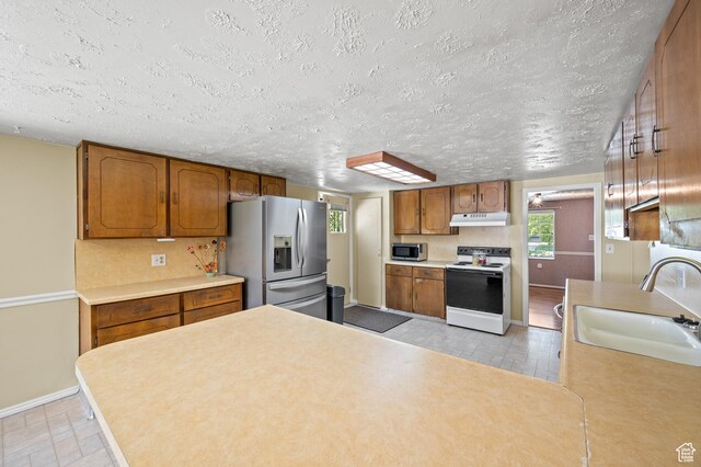 336 W 200 N, Bountiful, UT 84010 - kitchen featuring a sink, brown cabinetry, stainless steel appliances, under cabinet range hood, and baseboards