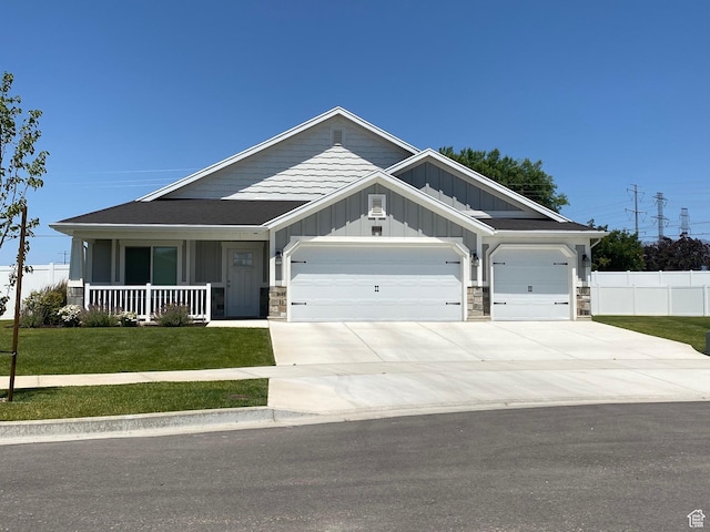 craftsman inspired home with concrete driveway, a front lawn, board and batten siding, fence, and a garage