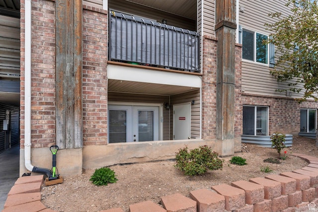 entrance to property with brick siding, a balcony, and french doors