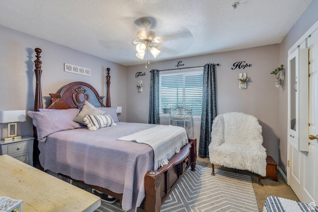 bedroom featuring a textured ceiling, light colored carpet, and ceiling fan